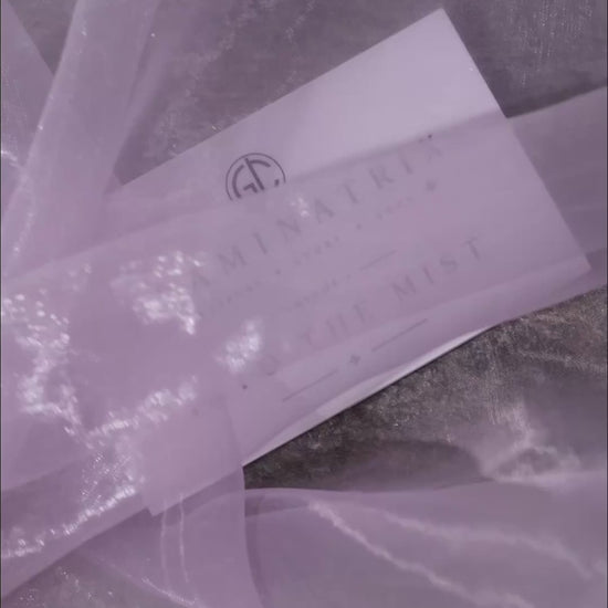 Close-up video of the Into the Mist pans on grey stone in drifting mist, ending on the white Volume I lid card set down on rocks