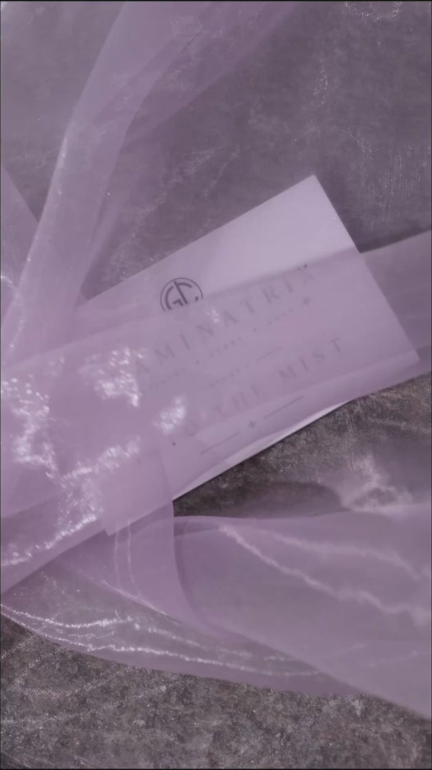 Close-up video of the Into the Mist pans on grey stone in drifting mist, ending on the white Volume I lid card set down on rocks
