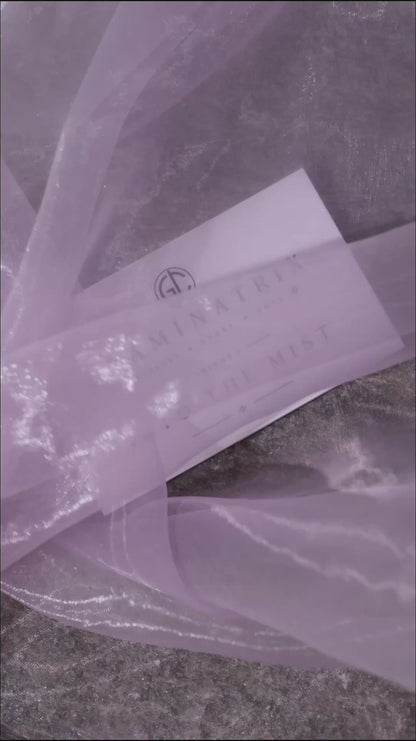 Close-up video of the Into the Mist pans on grey stone in drifting mist, ending on the white Volume I lid card set down on rocks