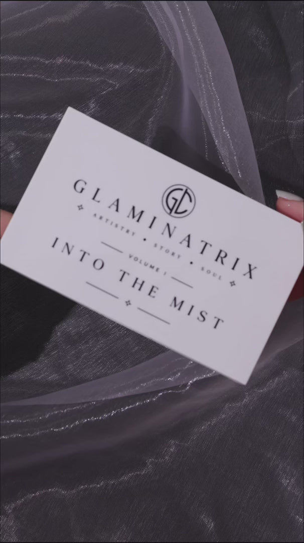 Video of Into the Mist finger swatches on a light and a deep skin tone over dark marble, with the lid card beside each arm