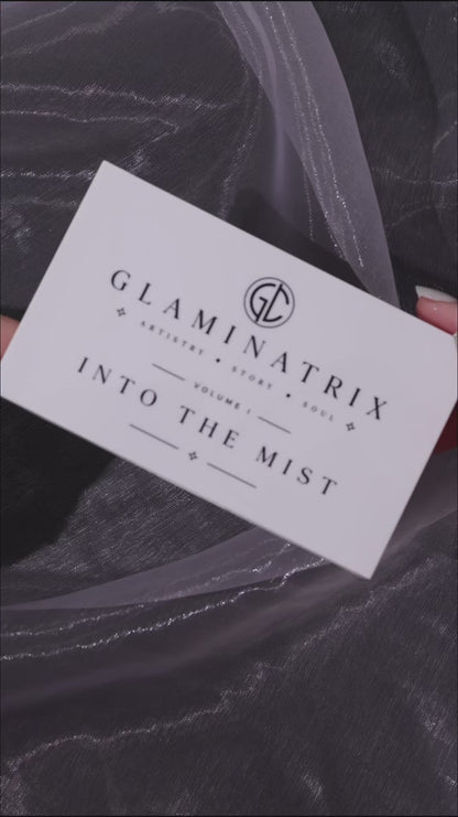 Video of Into the Mist finger swatches on a light and a deep skin tone over dark marble, with the lid card beside each arm