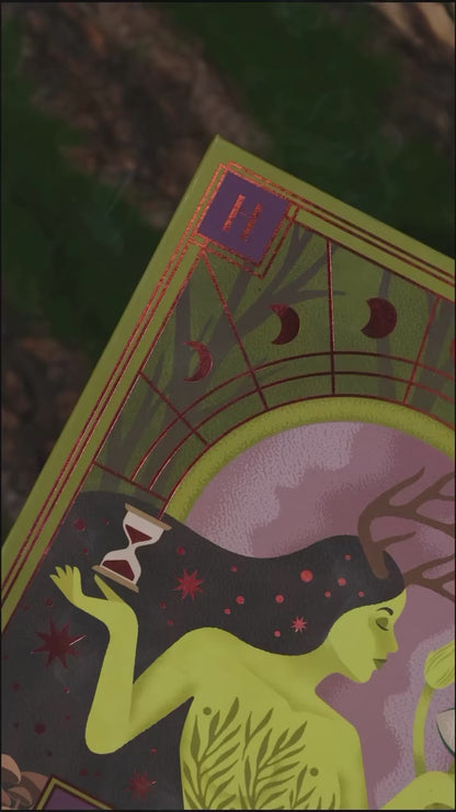 Video of The Huldra palette packaging close-up: a green-skinned figure with antlers holding an hourglass, framed by red copper moon phases