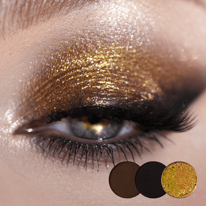 Close-up of an eye with gold shimmer across the lid and a smoky brown and black edge, brown, black and gold shade dots below.