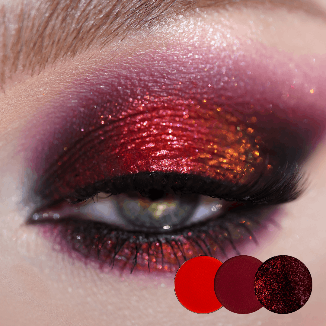 Close-up of an eye with red shimmer on the lid and a burgundy and pink crease, red, burgundy and dark red sparkle dots below.