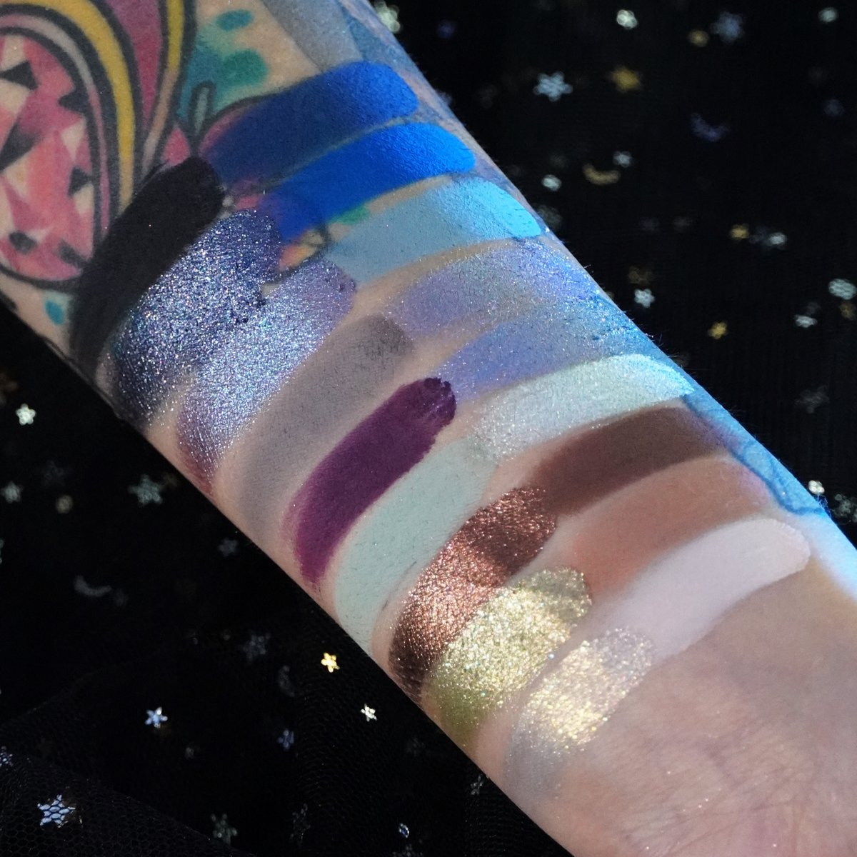 Gargoyle swatches on a tattooed arm over starry black fabric