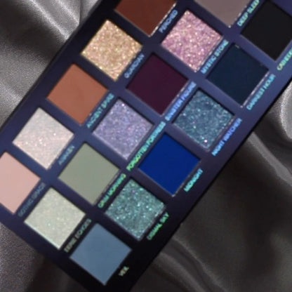 Close-up of the Mini Gargoyle palette on silver satin: labelled pans from pastel pink and sage to browns, plum, sparkling purple and teal, royal blue and slate