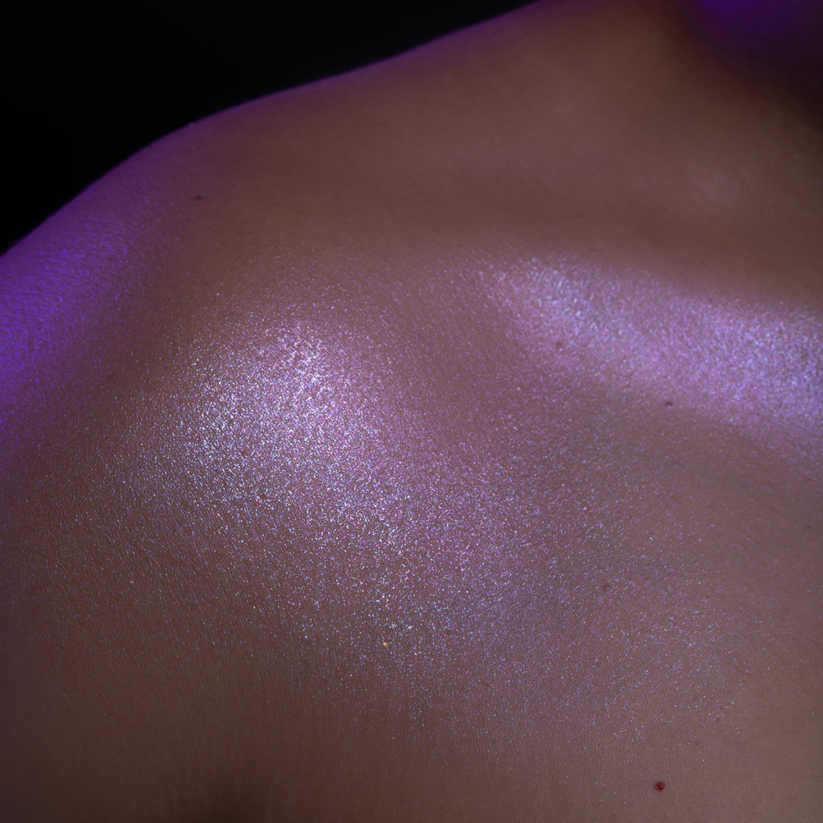 Phantom swatched on the shoulder and collarbone: a lilac reflective sheen on skin, lit in purple