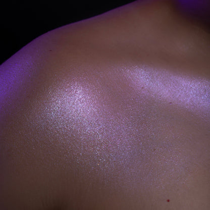 Phantom swatched on the shoulder and collarbone: a lilac reflective sheen on skin, lit in purple