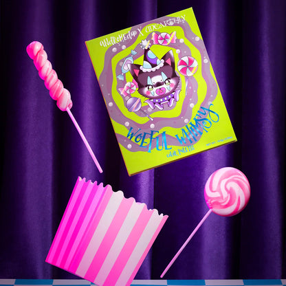 Woeful Whimsy palette by Unearthly Cosmetics - closed neon green box showing the Andromeda x Unearthly artwork and candy props against a purple draped backdrop